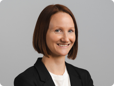 Portrait einer lachenden Frau mit rötlichem Bob, weißem T-Shirt und schwarzem Blazer